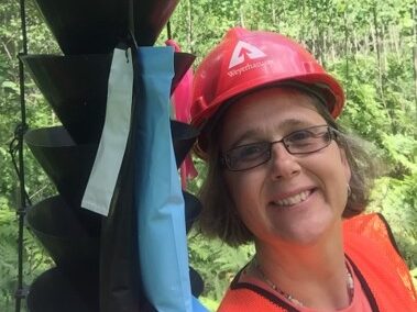 womon in hard hat beside black hanging insect trap