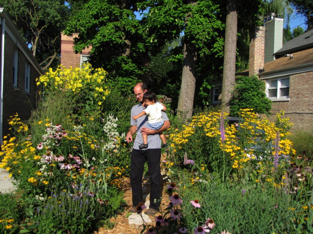 man and child standing in flower garden
