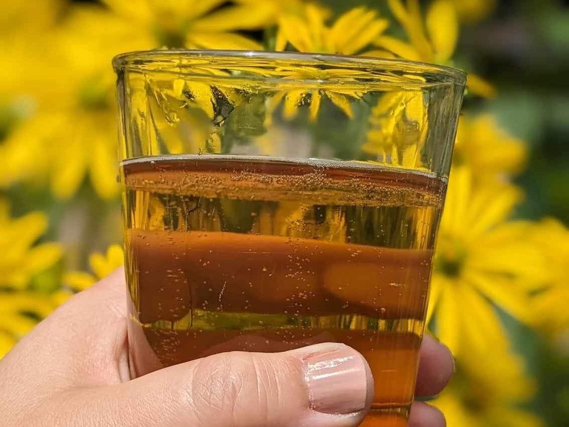 glass of beer against a yellow flower background